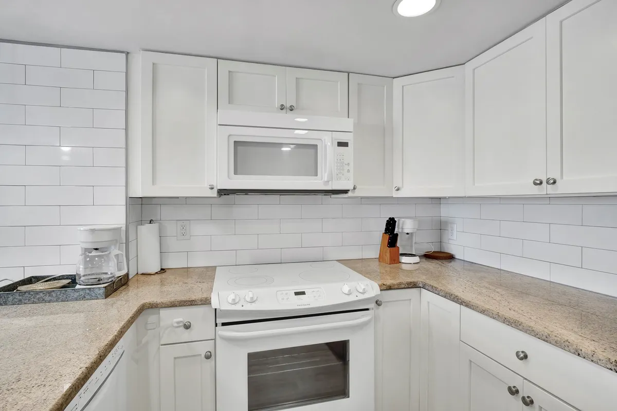 A modern kitchen scene with stainless steel microwave, granite countertop, and white cabinetry, evoking an inviting and functional atmosphere for meal preparation and dining.
