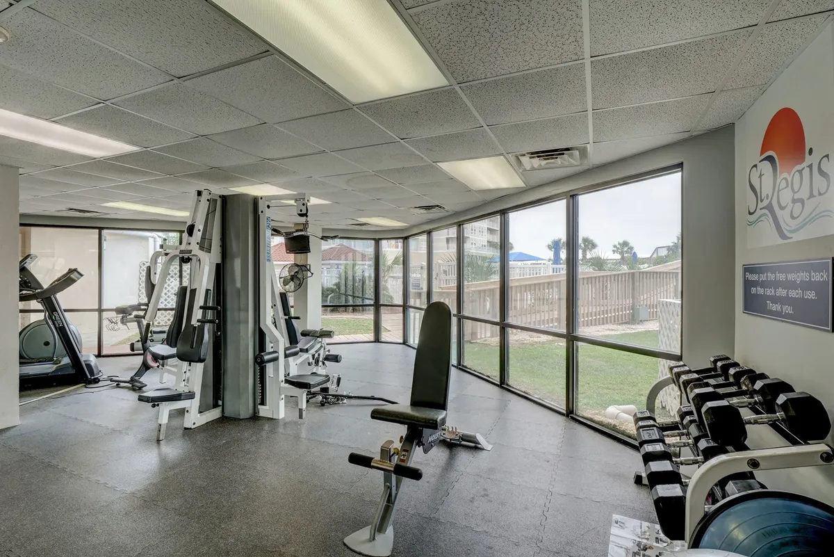 An inviting fitness center filled with exercise machines and free weights, bathed in natural light from large windows. The space feels fresh and motivating—perfect for couples looking to enjoy wellness amenities together during their stay.