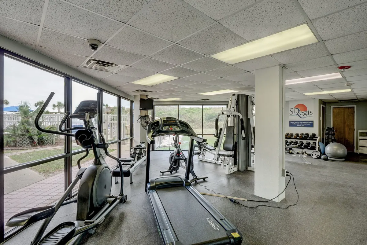 A bright and modern fitness center with treadmills, ellipticals, weight training equipment, and large windows that let in plenty of natural light. The space is energetic and motivating, designed for cardio, strength training, and group fitness activities.