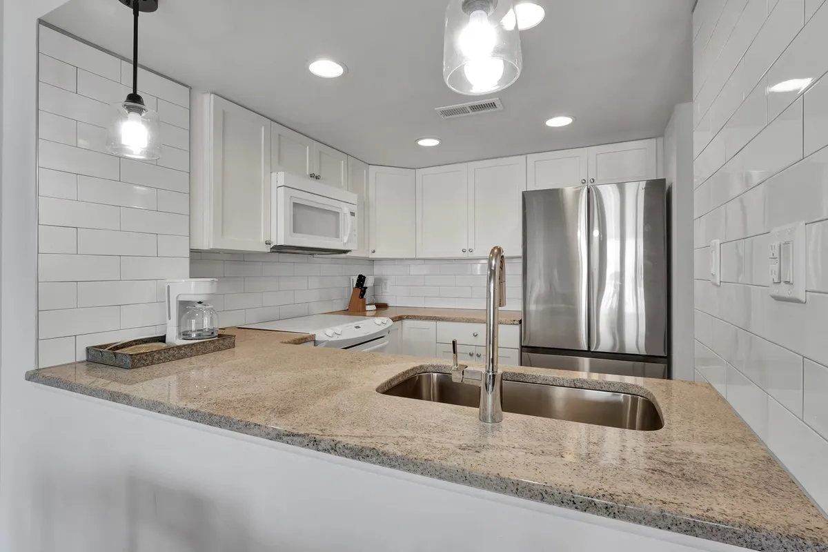 A contemporary kitchen with granite countertops, stainless steel appliances, white cabinetry, and a spacious island ideal for meal prep or socializing. The inviting layout suggests an environment where cooking and entertaining effortlessly blend.